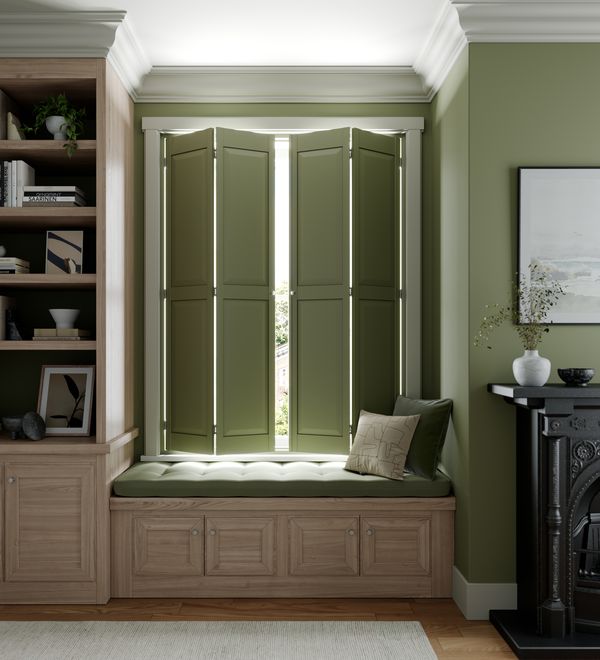 green solid wooden shutters in an alcove with the colour of the shutters matching the colour of the wall and the green cushion of the alcove