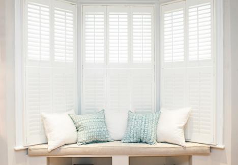 bay window with a sofa and white window shutters