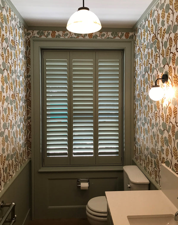 closed wooden shutters in a narrow toilet room with floral wallpaper