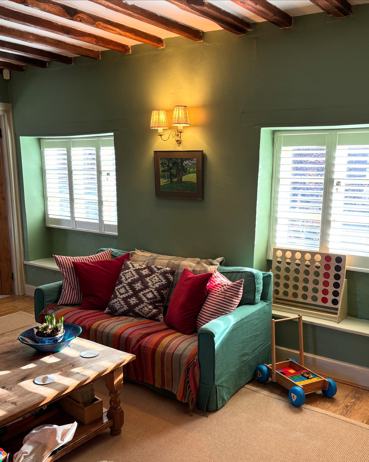White plantation shutters in a characterful green sitting room