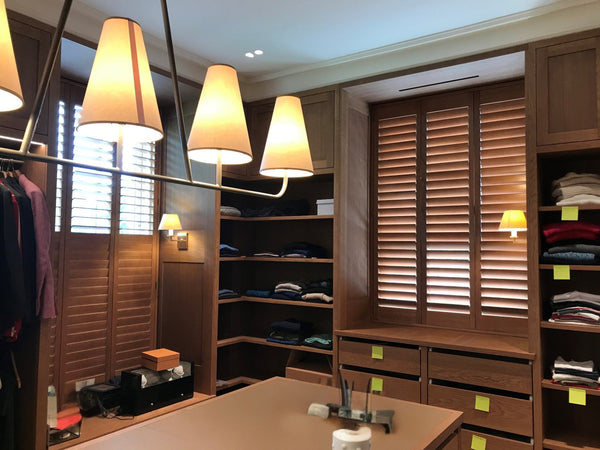 Modern bedroom with wooden wardrobe, bed, and hanging clothes.