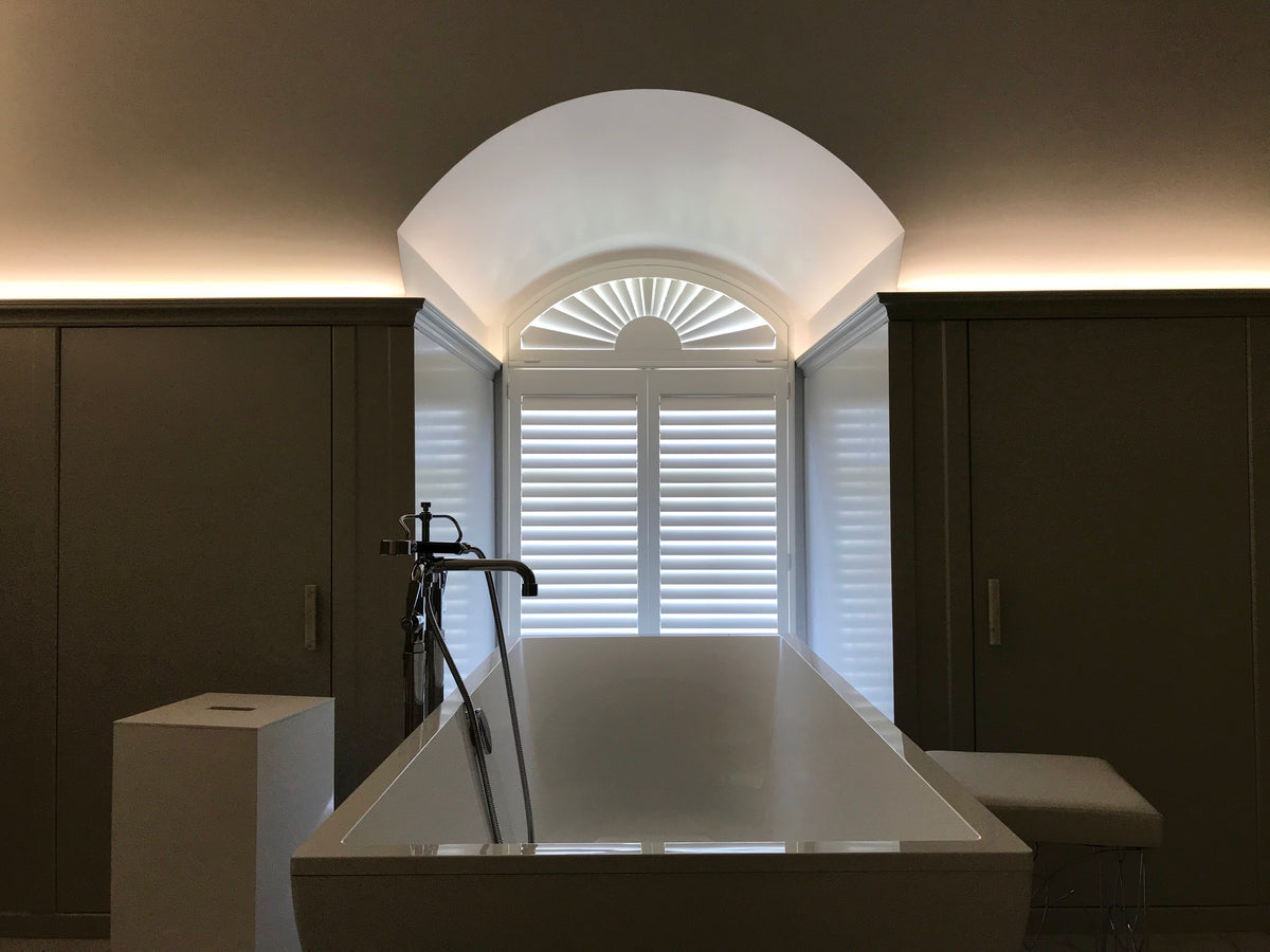 Complete arched bathroom window fitted with made-to-measure white shutters
